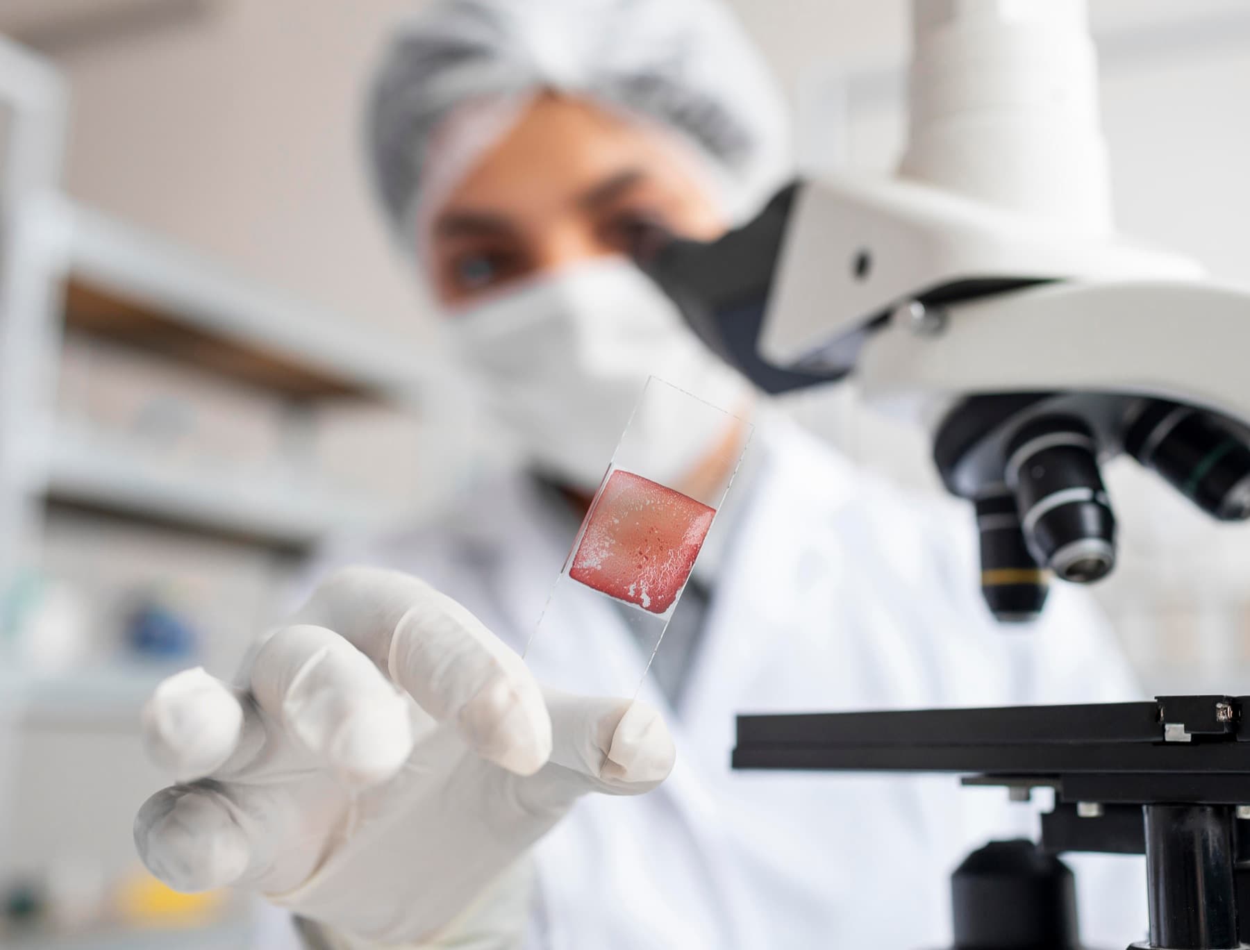 Researcher examining a sample slide at a microscope